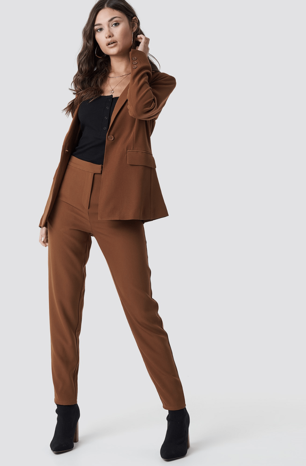 model wearing a brown suit, black top and booties